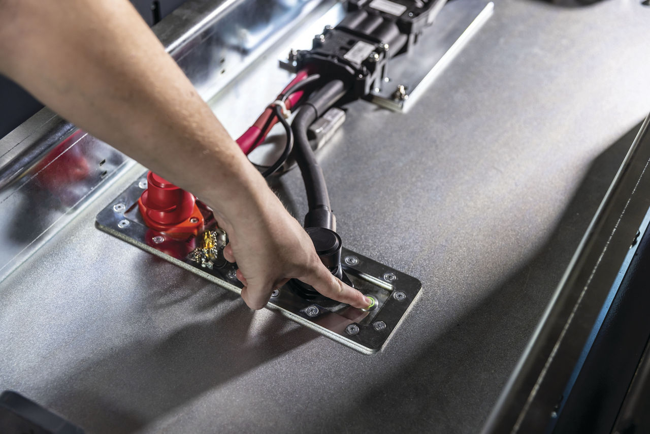 person's hand pressing power button on lithium-ion charger