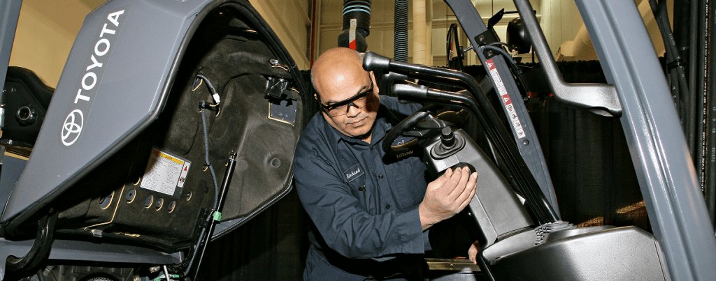 Close up of a male forklift technician inspecting the inside of a forklift. 