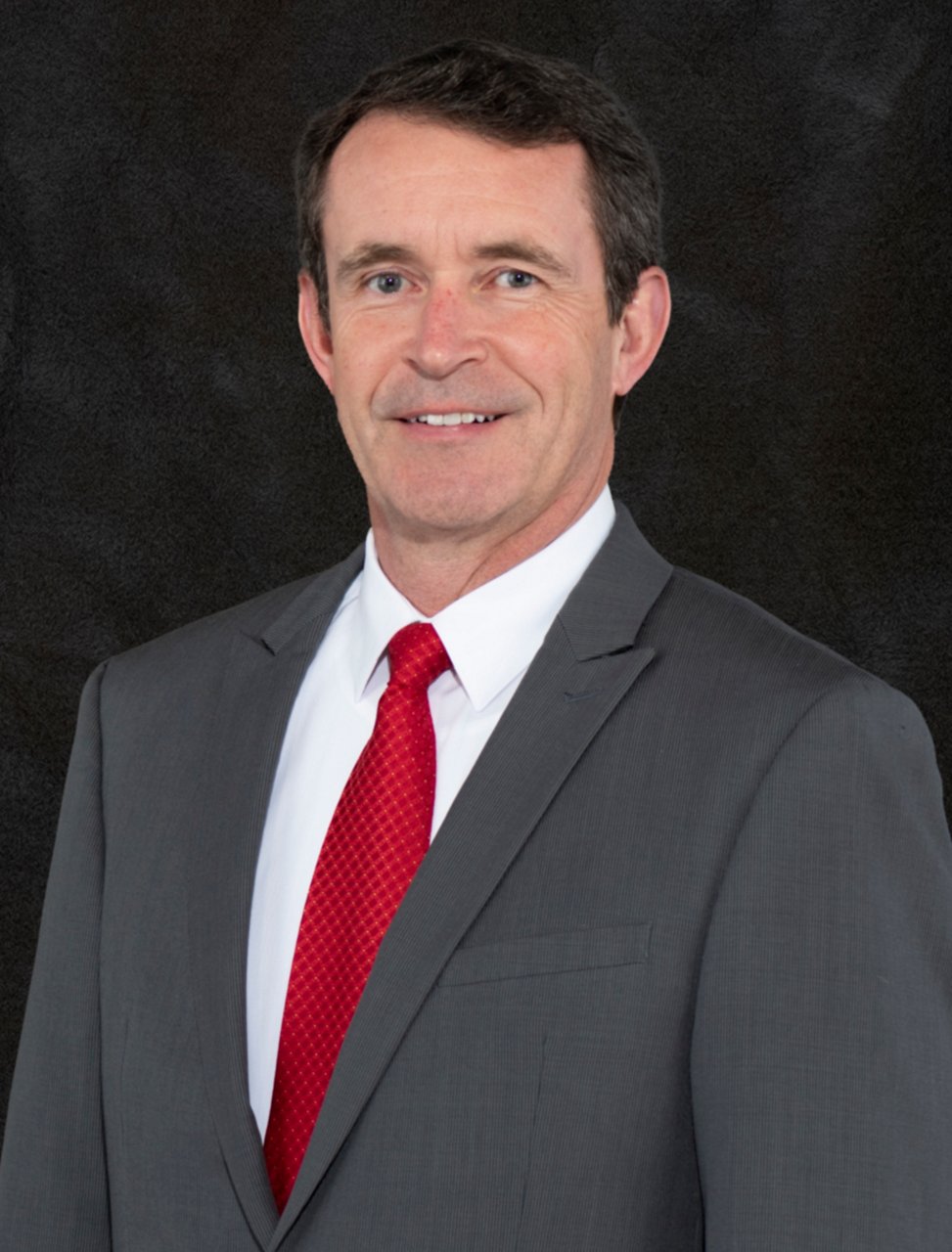 Foto de Mike Field en traje gris con corbata roja