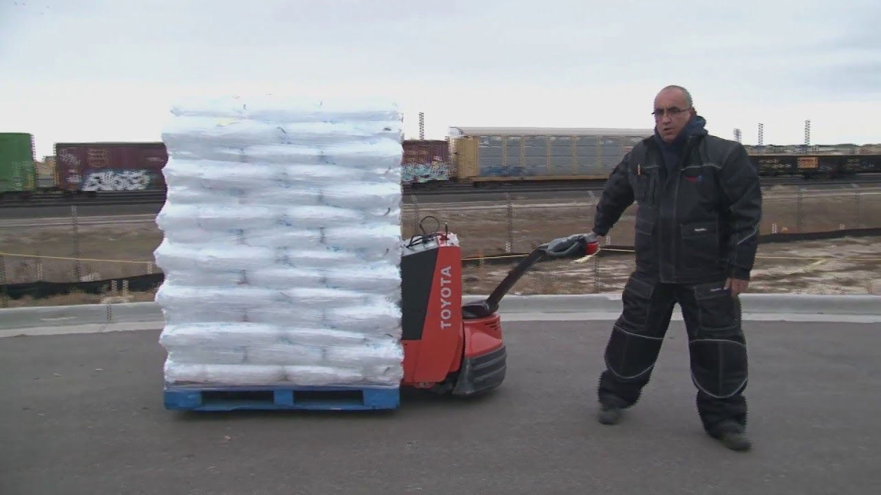 Un homme utilise un walkie électrique Toyota pour transporter plusieurs sacs de glace dans un parc de marchandises extérieur 