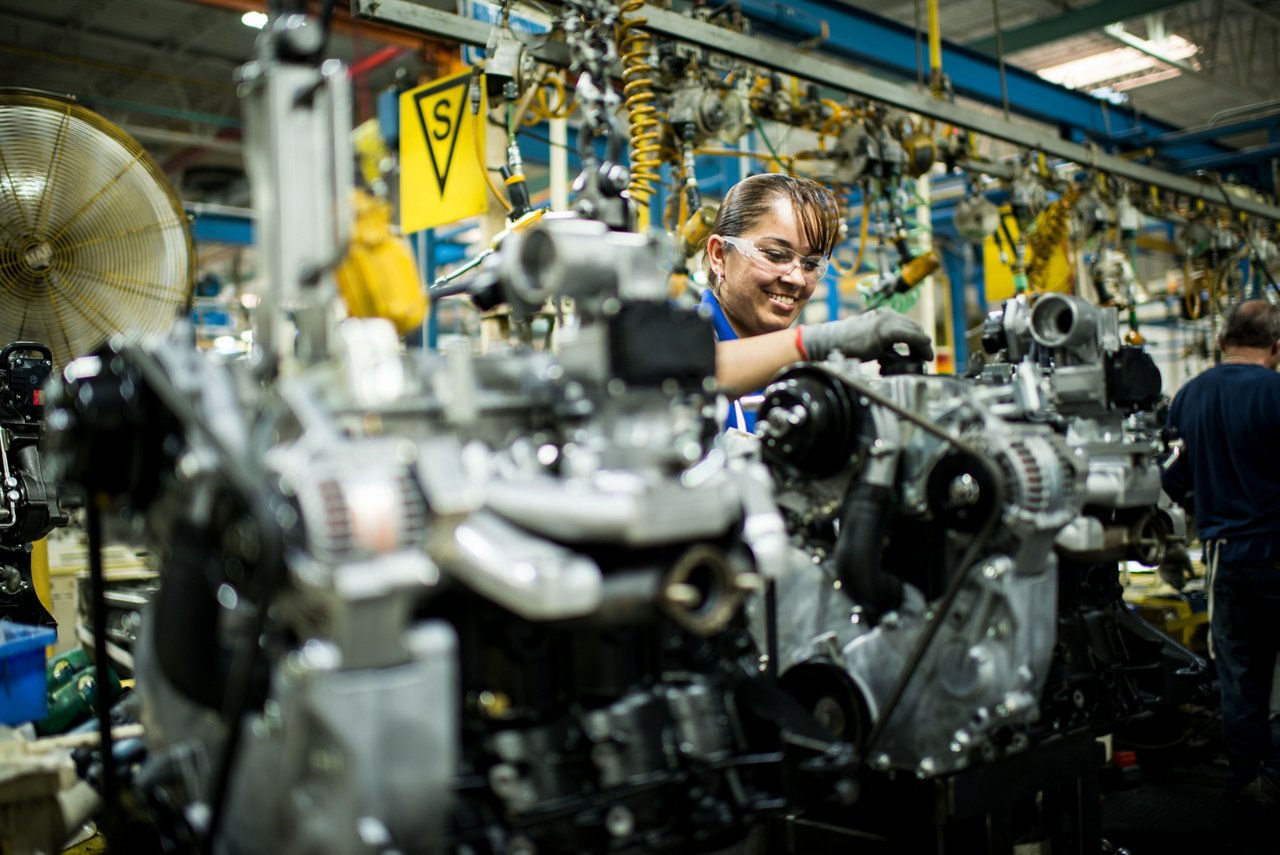Female technician smiling while working on Toyota Forklift parts in warehouse 