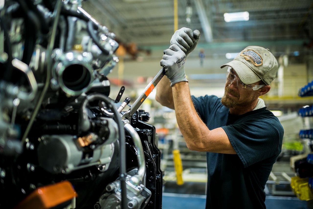 Employé de fabrication Toyota utilisant une clé à molette sur un moteur de chariot élévateur