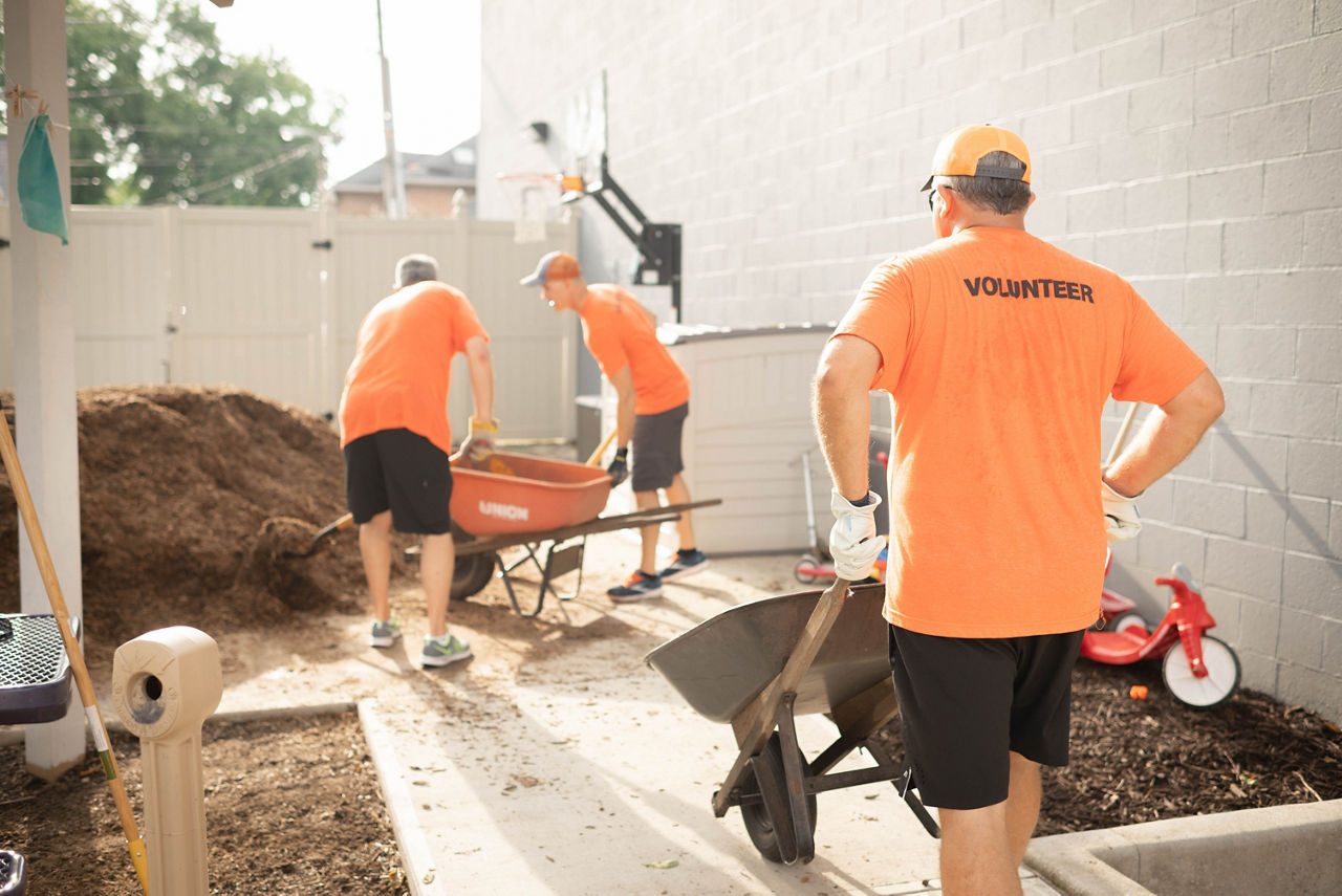 3 tmh employees dig dirt into wheel barrels to volunteer for turning point 