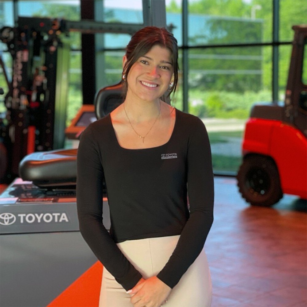 Pasante de Toyota sonriendo frente a una carretilla elevadora